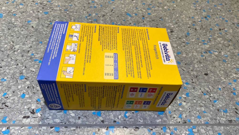 Rückseite der Verpackung einer getesteten Folgemilch auf einer grauen Fläche.