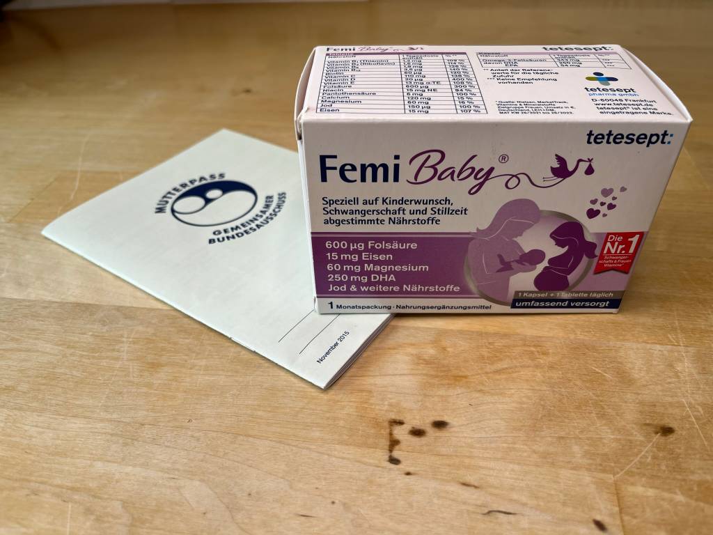 Folsäure Packung von Tetesept und ein Mutterpass auf einem Tisch.