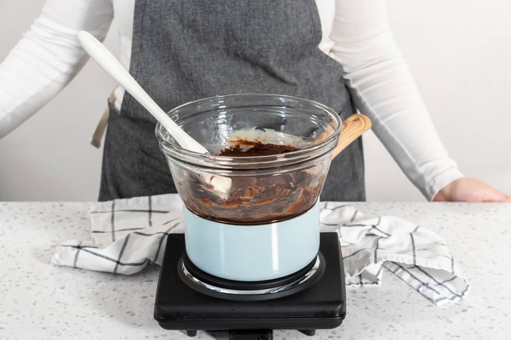 Fondue-Schokolade-Test: Jemand erhitzt Schokolade im Wasserbad. 