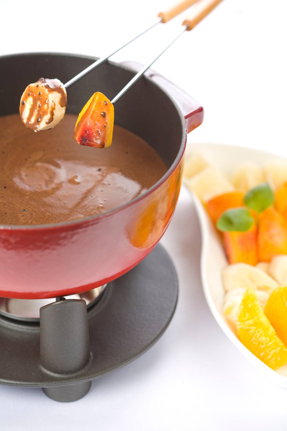 Fondue-Set-Gusseisen-Test: Fonduegabeln mit Früchten werden in ein Schoko-Fondue aus Gusseisen eingetunkt. 