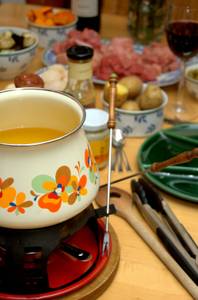 Fonde-Set-Gusseisen-Test: ein Fondue-Set aus Gusseisen mit Blumenmuster steht auf einer reichhaltig gedeckten Tafel aus Holz.