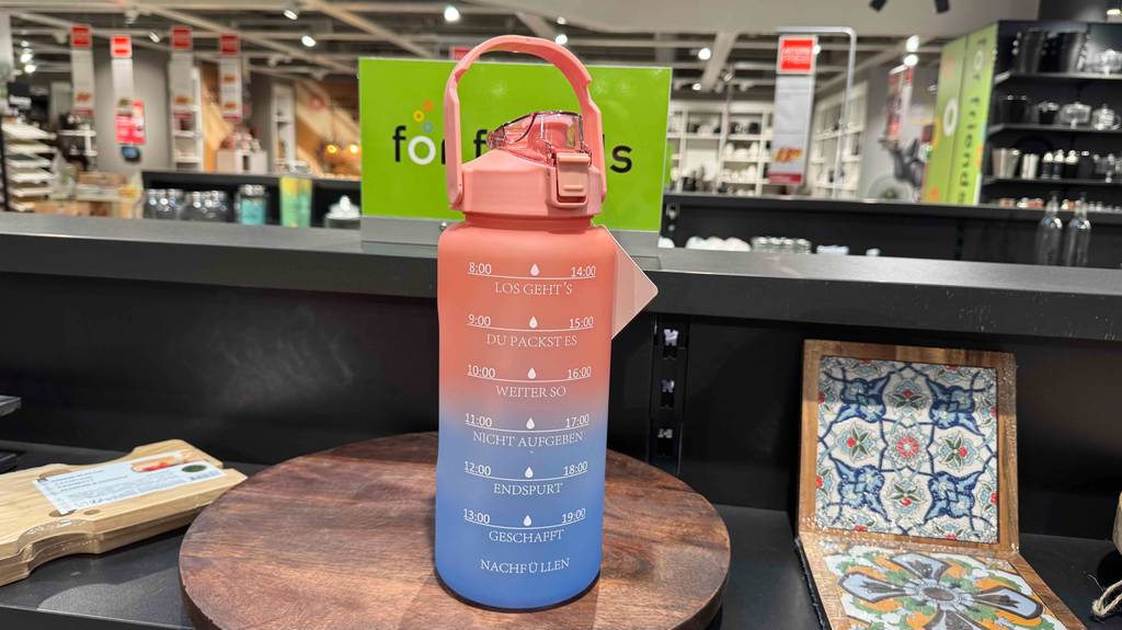 Eine getestete Trinkflasche 2 Liter steht mit der Mundöffnung nach vorn auf einem runden Holztisch.