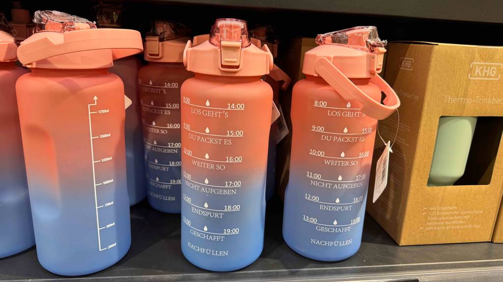 Im Test: Mehrere Trinkflaschen 2 Liter mit lustiger Zeittabelle stehen in einem Regal.