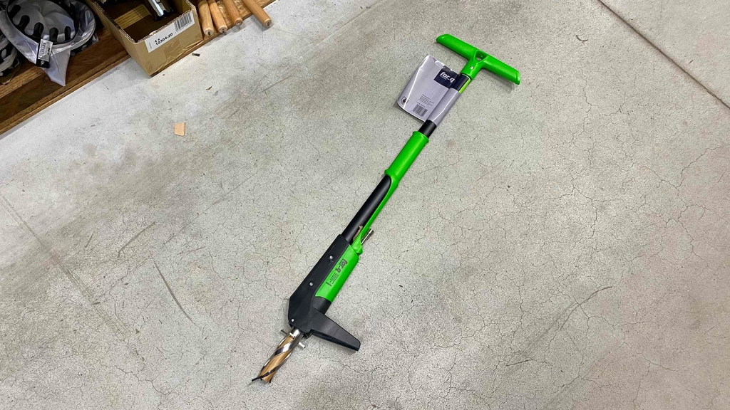 Ein schwarz-grüner Unkrautstecher im Test liegt auf einem grauen Zementboden.