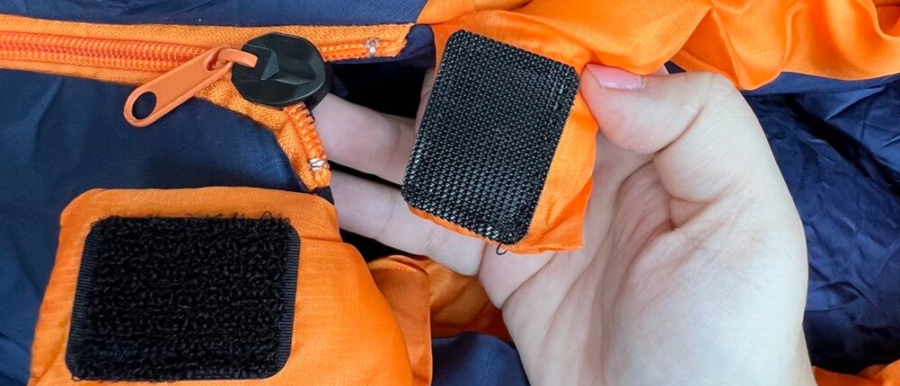 Hand hält Klettverschluss am Ende des Reißverschlusses des Forceatt O-SDMM-SCFYR-ZQ-C