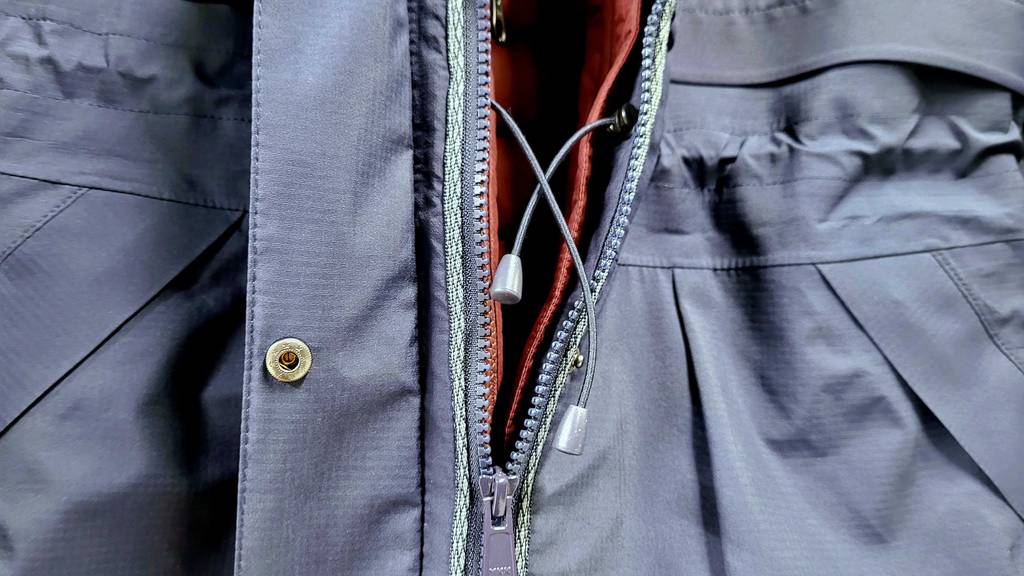 3-in-1-Jacke getestet: Detailansicht des Reissverschlusses inklusive Zugschnüre einer Jacke in Blau.