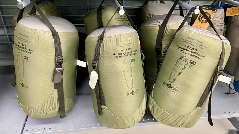 Outdoor-Schlafsack getestet: Mehrere originalverpackte Produkte nebeneinander in einem Verkaufsregal.