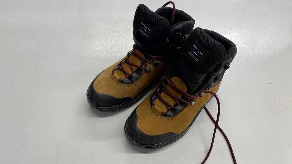Im Test: Forclaz Trekkingschuhe für Damen in ocker-schwarz stehen auf weißer Fläche.