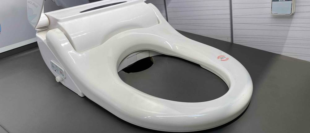 Nahaufnahme der Brille eines getesteten Dusch-WC Aufsatzes auf einer dunklen Fläche.