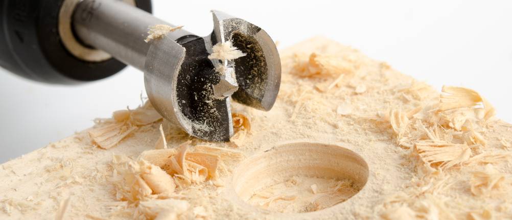 40-mm-Forsnterbohrer im Test: Eine gebohrte Aussparung, daneben liegt ein Forstnerbohrer.