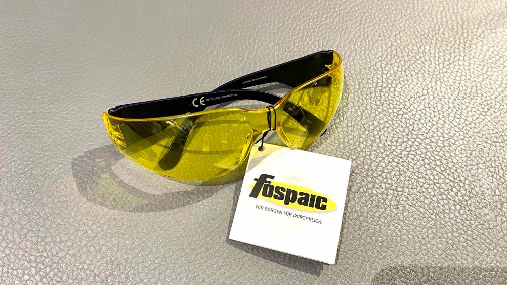 Im Test: Eine gelbe Motorradbrille mit Label von vorne auf einer hellen Fläche.