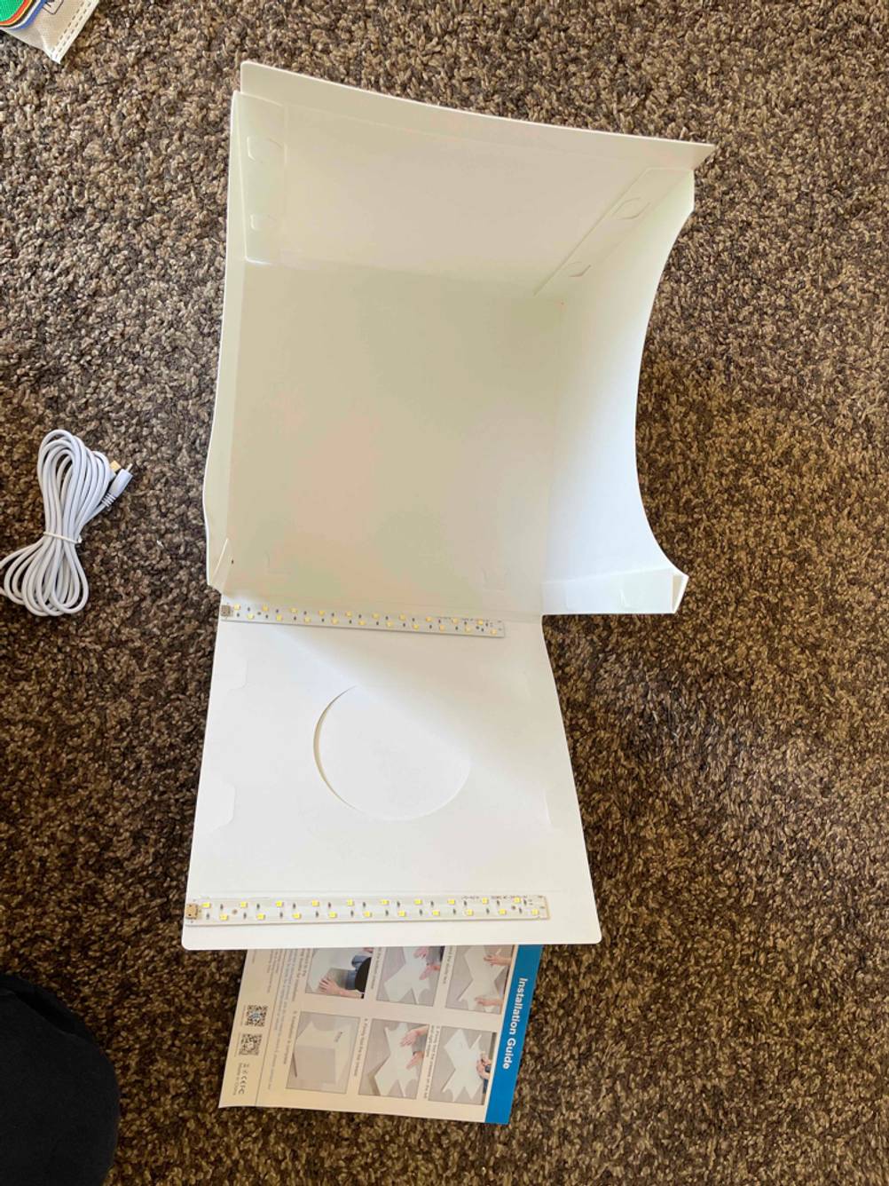 Eine teilaufgebaute Fotobox im Test auf einem brauen Teppich.