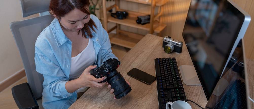 Person bearbeitet Fotografien an einem häuslichen Arbeitsplatz.