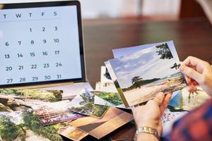 Fotokalender getestet: Frau gestaltet einen Kalender am PC und schaut sich Urlaubsfotos an. 