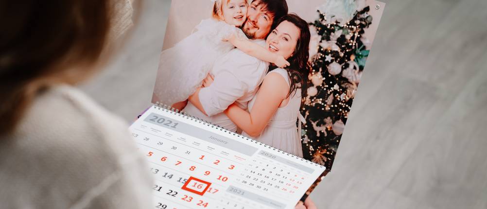 Test von Fotokalendern: Eine Frau schaut sich auf einem Fotokalender ein Familienbild an.