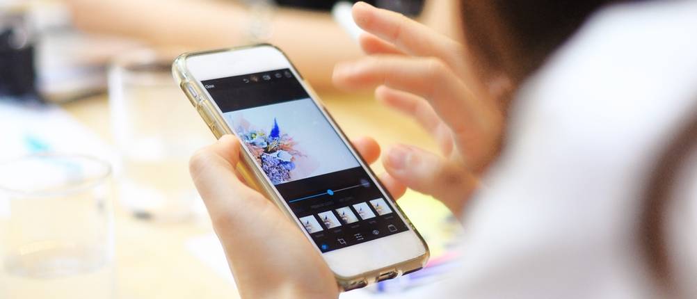 Hand bearbeitet ein Foto in einer App auf dem Smartphone