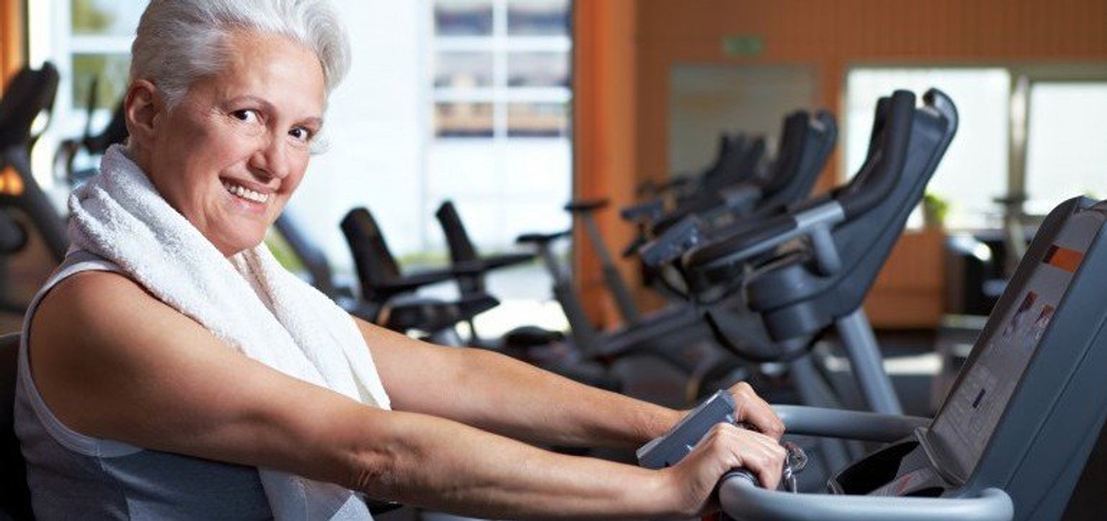 Ältere Frau trainiert auf einem Liegeergometer