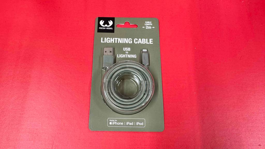 Ein verpacktes Lightning-auf-USB-C-Kabel liegt zum testen auf einer roten Fläche.