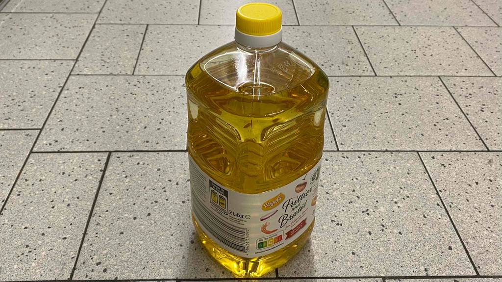Eine Flasche getestetes Frittieröl steht auf dem Boden. 
