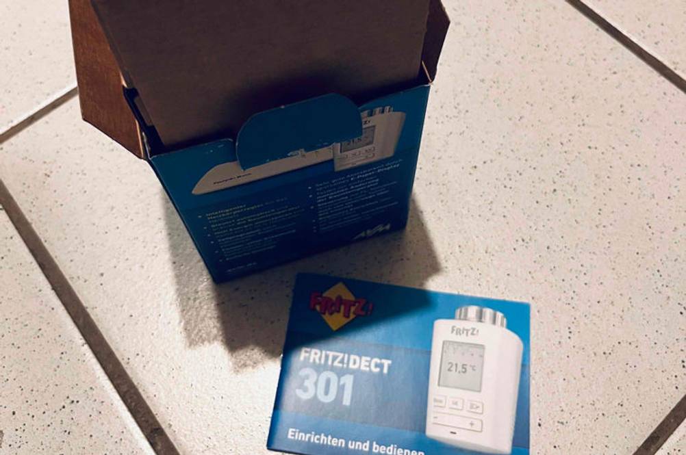 Smart-Home-Heizkörperthermostat im Test: Karton von einem Fritz-Smart-Home-Heizkörperthermostat steht geöffnet auf einem weißen Boden.
