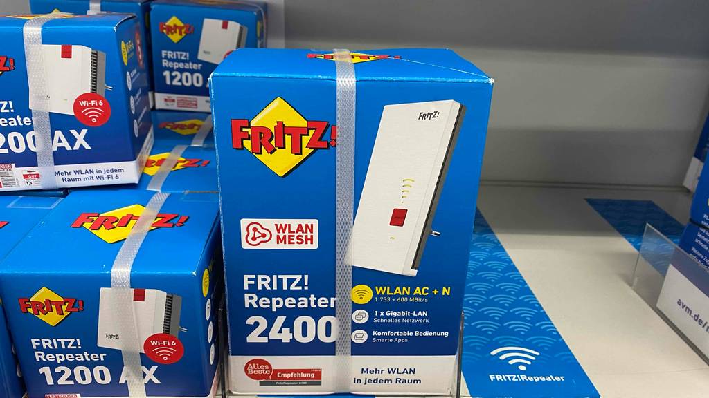Getesteter Fritz-WLAN-Repeater mit LAN-Anschluss steht in seiner Verpackung in einem Verkaufsbereich neben anderen Modellen.