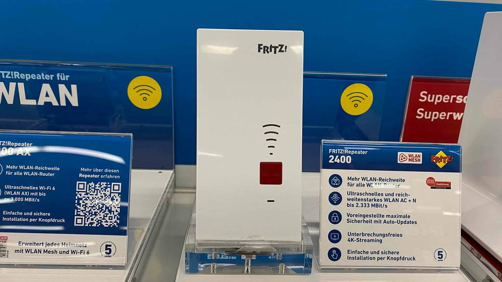 Fritz-WLAN-Repeater mit LAN-Anschluss im Test steht auf einem Verkaufsregal neben einem Informationsschild.