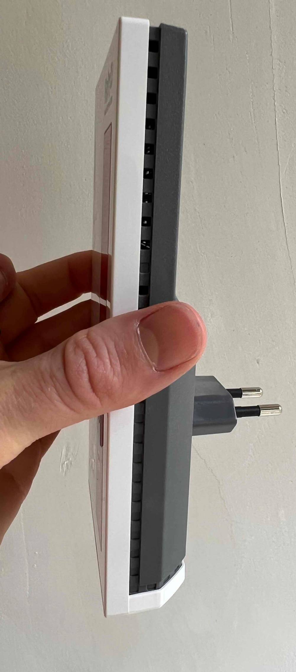 Hand hält einen getesteten WLAN Repeater und zeigt die Seitenansicht.