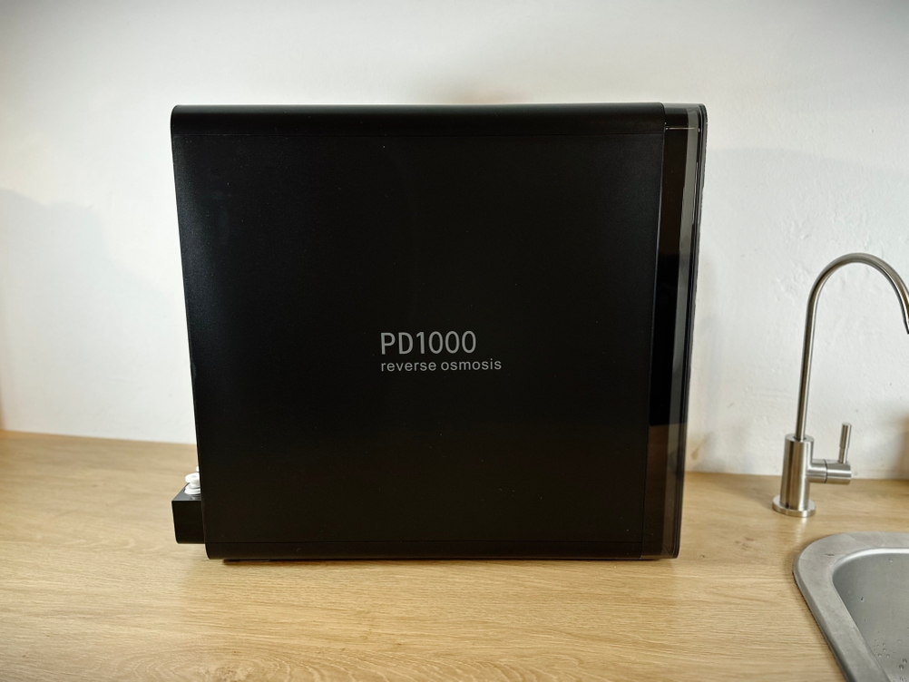 Das Bild zeigt die Frizzlife PD1000-TAM4 von der Seite, aufgestellt in einem Spülenschrank. Der pH+ Filter ist daneben sichtbar.