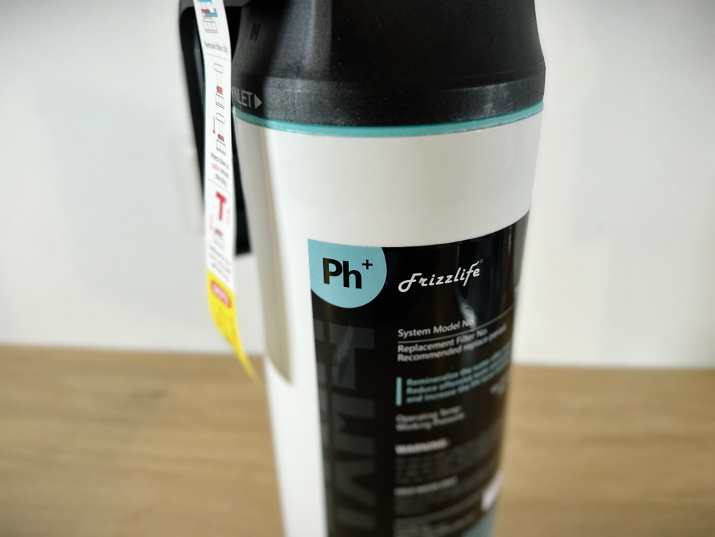 Zu sehen ist der separate pH+ Filter der Frizzlife PD1000-TAM4, der außerhalb des Hauptgeräts montiert wurde. Der Filter liegt auf dem Schrankboden.