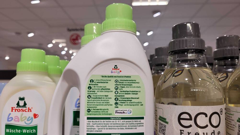 Im Test: Eine Flasche Baby-Waschmittel von hinten zwischen anderen Produkten stehend.