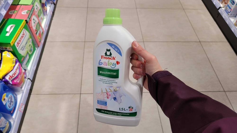Eine Hand hält eine Flasche Baby-Waschmittel im Test in einem Laden.