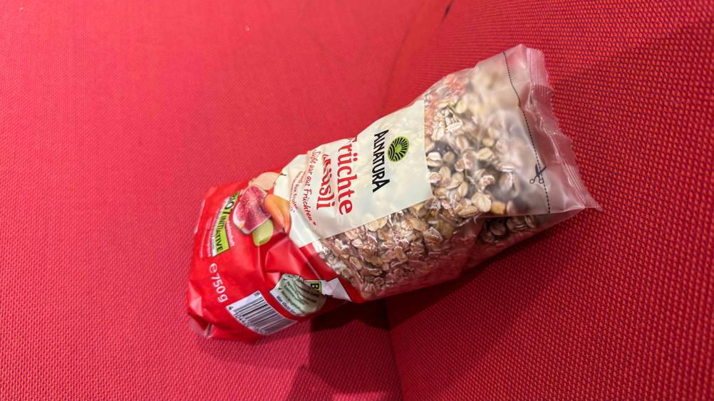 Früchte-Müsli getestet: Eine Packung seitlich von oben auf einem roten Polster.
