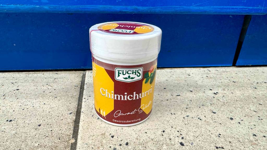 Ein getestetes Chimichurri-Gewürz in der Dose mit Dosierkappe steht vor einem blauen Regal.