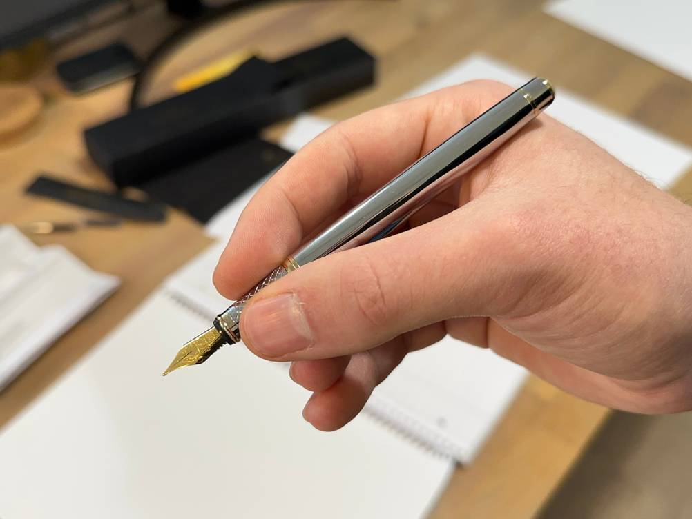 Der Scriveiner Silver Fountain Pen wird in der Hand gehalten.