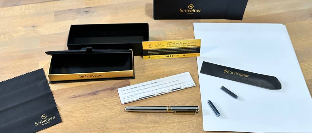 Der Lieferumfang des Scriveiner Silver Fountain Pen liegt auf einem Schreibtisch.