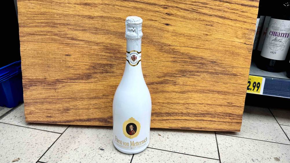 Fürst-von-Metternich-Sekt getestet: Eine Flasche steht vor einem Holzbrett auf dem Boden.