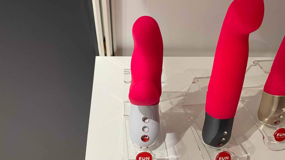Ein Fun-Factory-Vibrator im Test von vorne in einem hellen Regal neben anderen Produkten.
