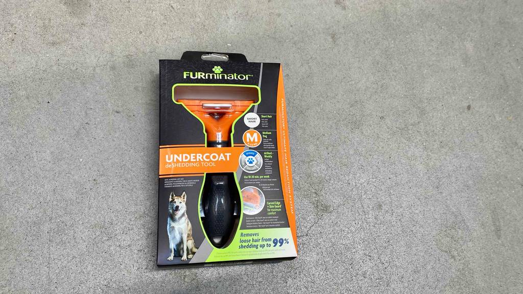 Hundescheren im Test: eine schwarze Packung mit einem Undercoat-Modell liegt auf einem Zementboden.