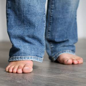 Zwei nackte Füße auf Laminatboden.