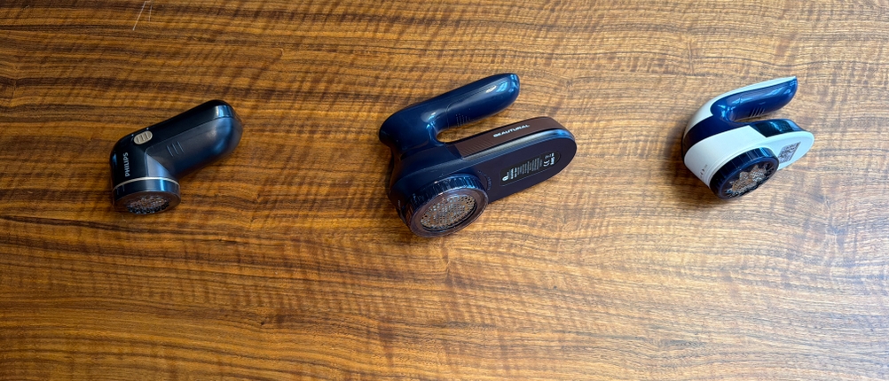 Drei Fusselrasierer liegen nebeneinander auf einem Tisch