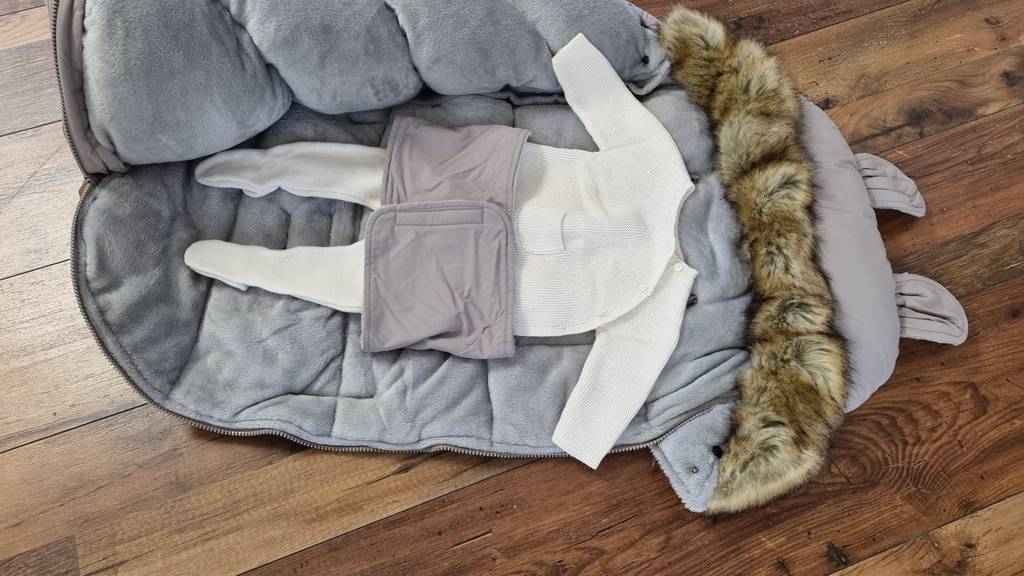 Fußsack ganz geöffnet mit Babykleidung.