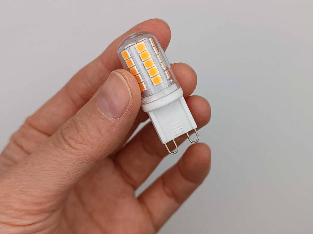 G9-LED getestete: Eine Hand hält eine Leuchte vor einer hellen Wand.