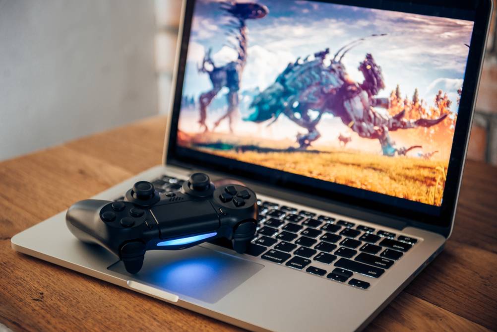 Ein getesteter Asus-ROG-Laptop mit Controller auf der Tastatur steht auf einem Tisch.