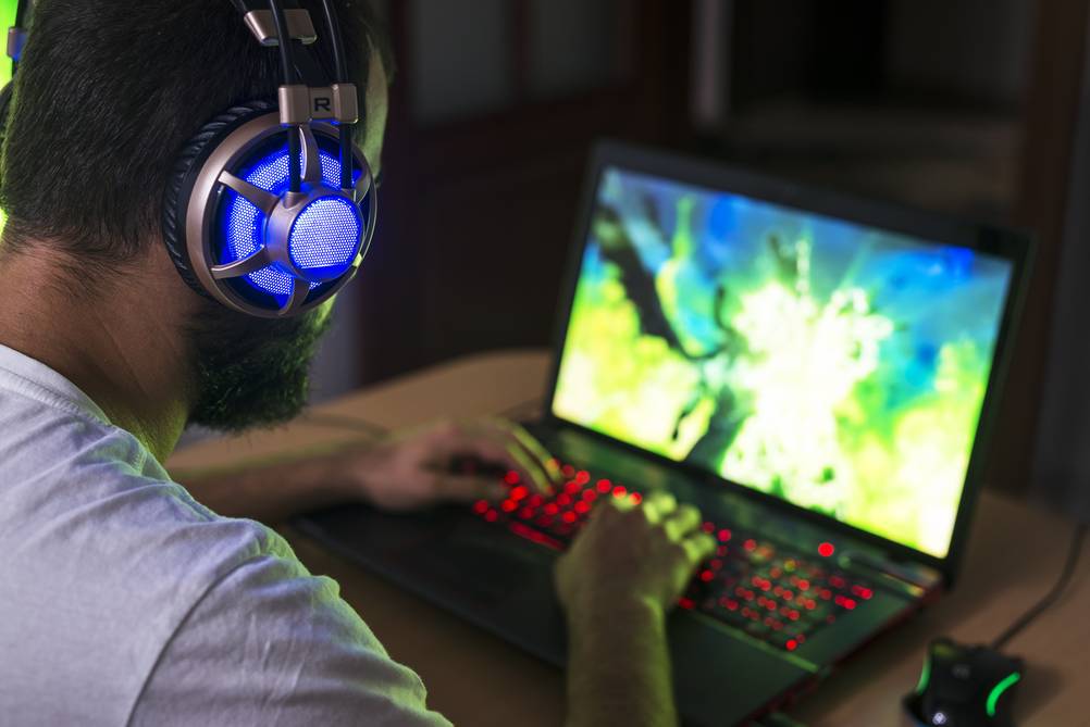 Ein Gamer mit Kopfhörern sitzt vor einem getesteten Asus-ROG-Laptop.