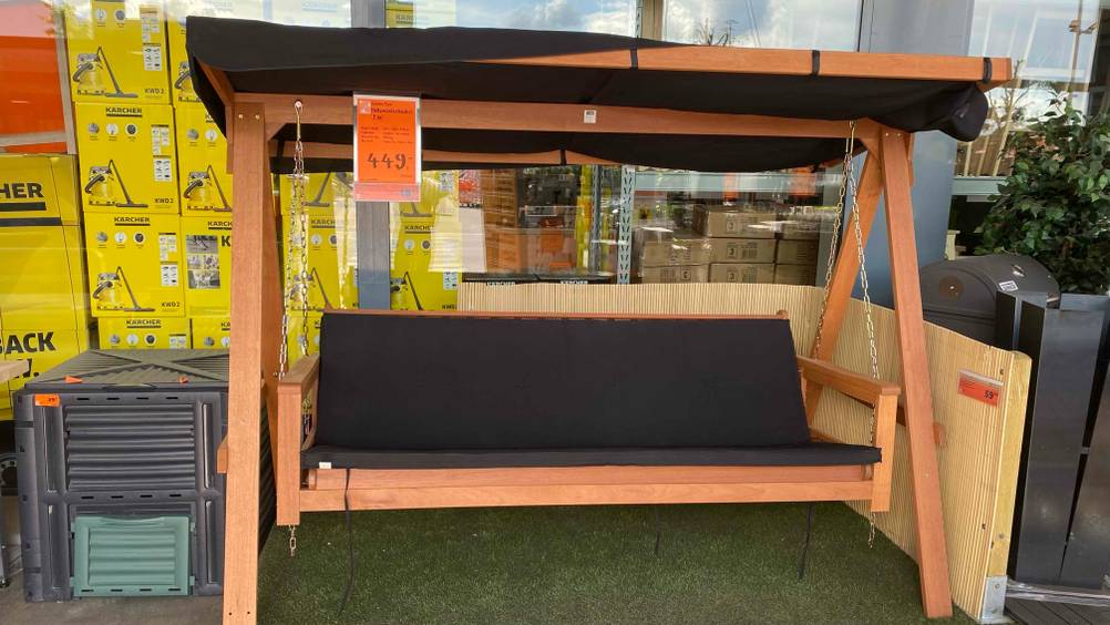 Im Test: Eine Hollywoodschaukel (Holz) mit Preisangabe von vorne zwischen anderen Produkten stehend.