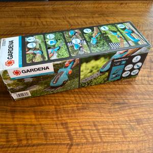 Der Karton der Gardena ComfortCut Li 9888-20 steht auf einem Holztisch.