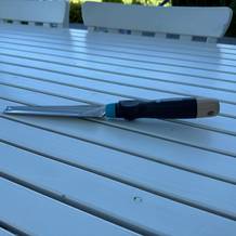 Der Gardena-EcoLine-Unkrautstecher (17702-20) liegt auf einem Holztisch.