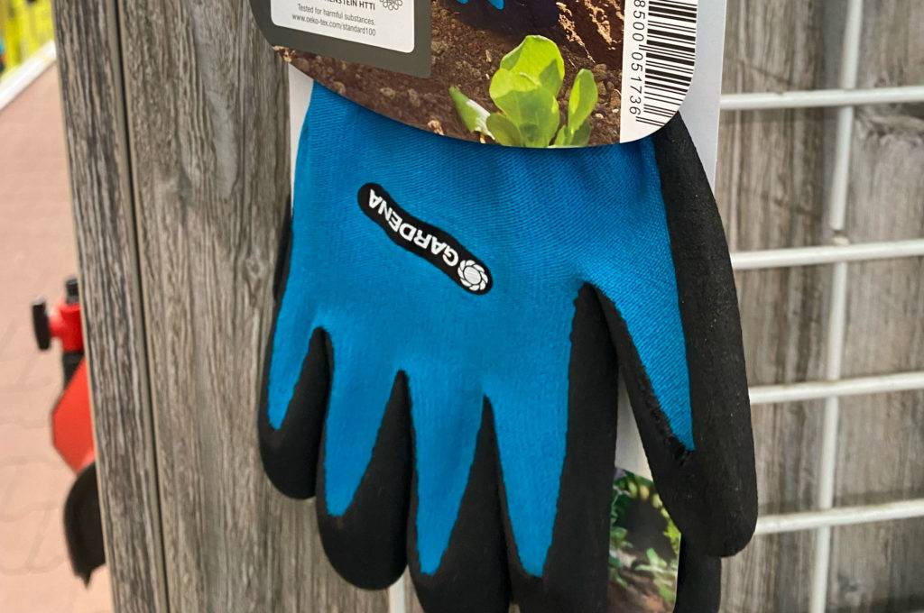 Neopren-Handschuhe im Test: blaue Gardena-Handschuhe hängen an einem Verkaufsstand.