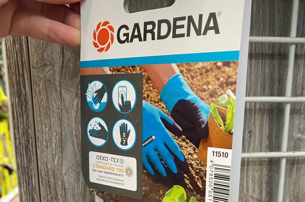 Neopren-Handschuhe im Test: blaue Gardena-Handschuhe hängen an einem Verkaufsstand.