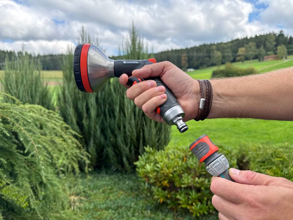 Eine Hand steckt die Gardena-Premium-Multibrause (18317-20) an einen Schlauch